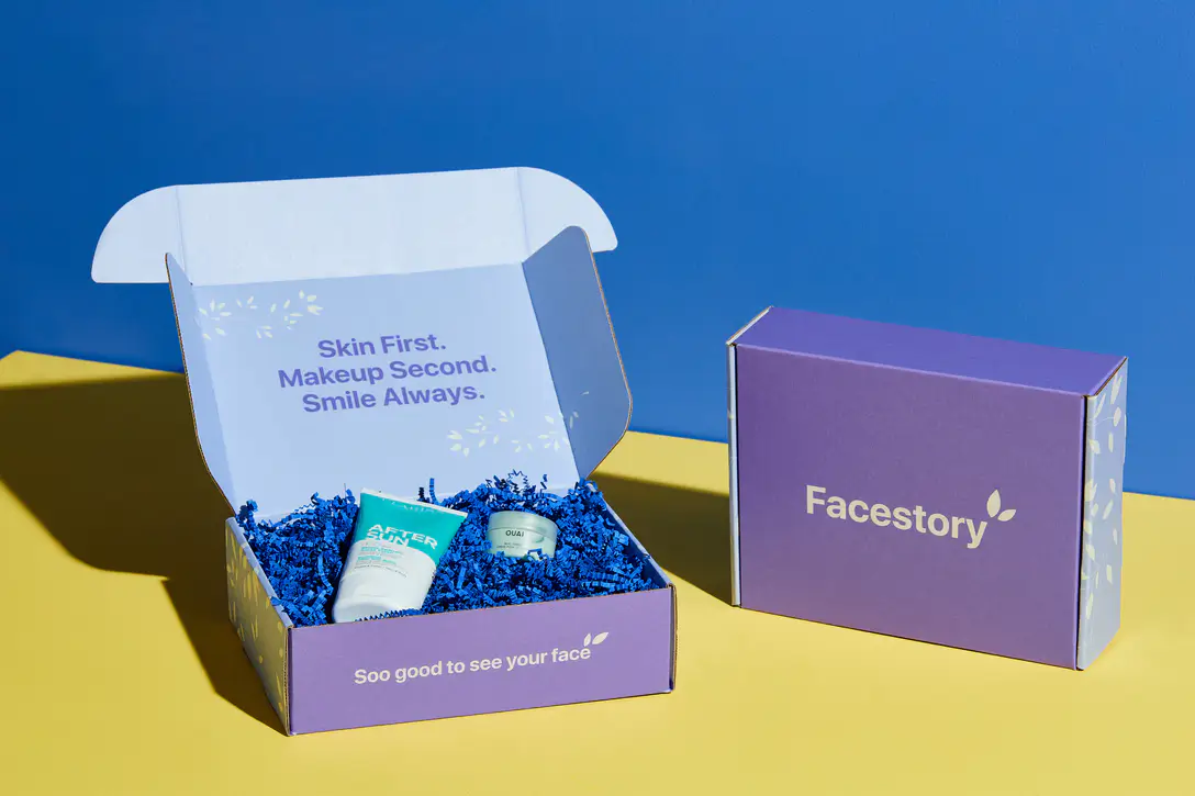 Open custom mailer box with a printed message inside the lid and blue crinkle paper, beside a closed matching mailer